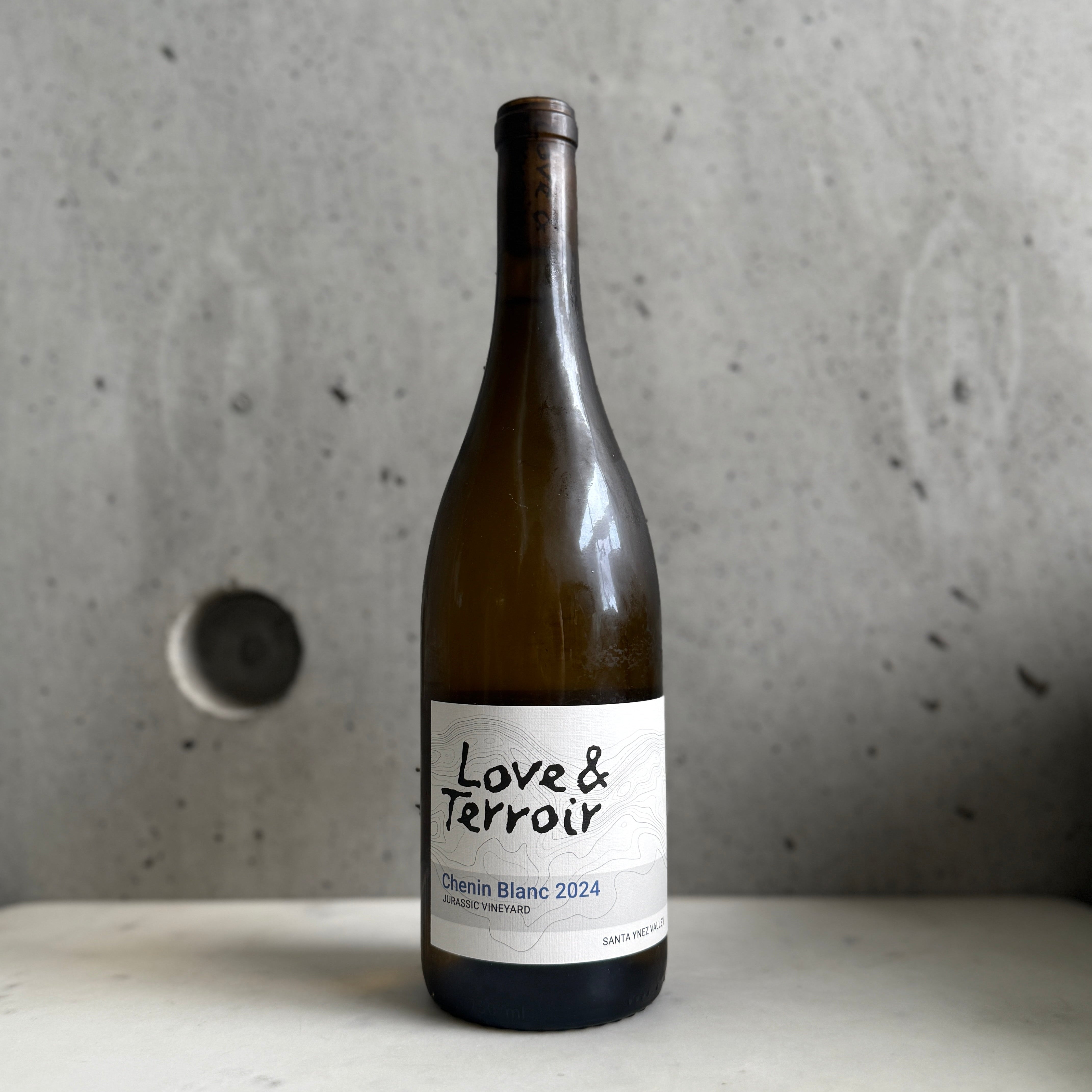 Love & Terroir Chenin on a concrete surface with a gray background